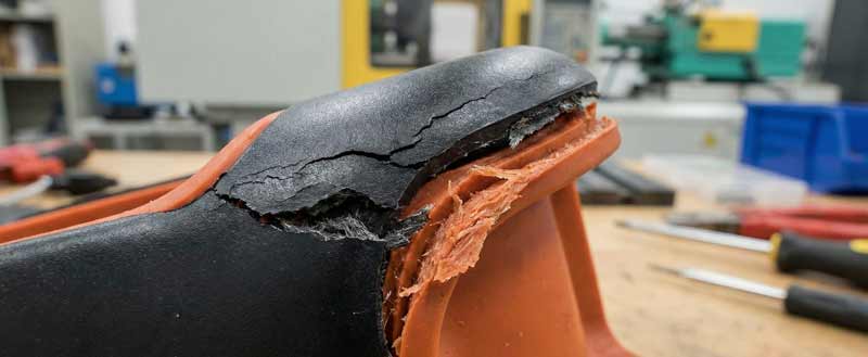 mehrfachkomponenten spitzgussteil in orange und schwarz mit einer ecke die delamination aufweist