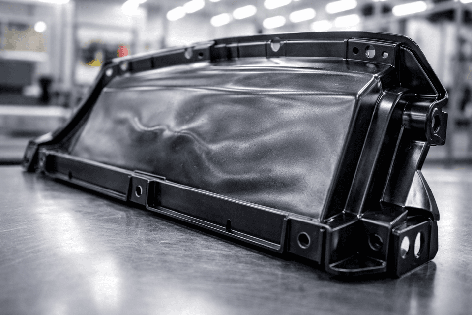 Plastic injection molded part showing warping with visible surface distortions in an industrial setting